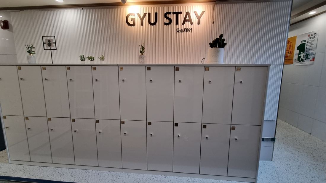천안 고시원 규스테이 GYU STAY 로고 아래 칸마다 문이 달린 수납장